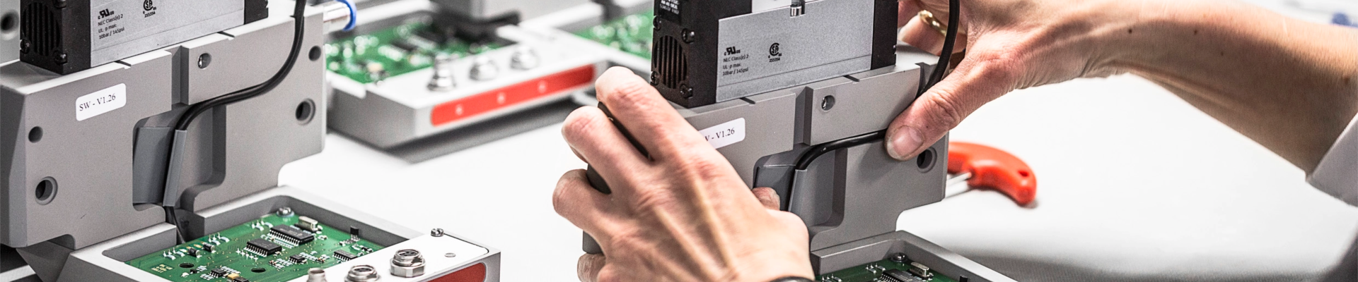 two hands work on a circuit board in Baumer hhs production